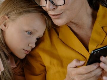 Senior woman and young girl enjoying time together, bonding over a smartphone indoors.
