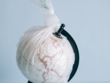 A globe wrapped in plastic highlights the pressing issue of global pollution and environmental conservation.