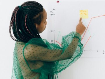 Focused woman points to financial graph, showcasing analysis & strategy.
