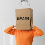 A person wears a box labeled 'brain' while discarding 'rubbish' paper, symbolizing mental clutter.