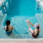 Two women enjoying a relaxing moment in an indoor swimming pool. Perfect for wellness and leisure themes.