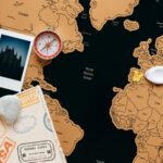 Flat lay of travel items including a map, compass, and polaroid for adventure planning.