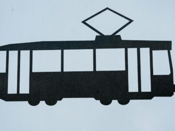 Silhouette of a tram sign symbolizing public transportation, isolated on white.