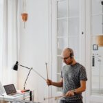 Adult musician plays electronic mallet instrument indoors, capturing a modern musical moment.