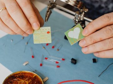 A detailed close-up of hands assembling electronics with circuit boards and soldering.