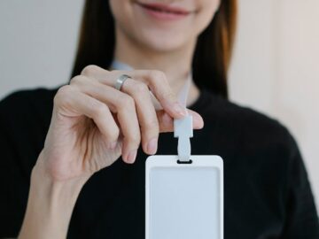 Portrait of a cheerful woman holding a blank ID badge, perfect for business or event promotion.