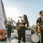 A diverse band performs outdoors at sunset, showcasing various musical instruments and talent.