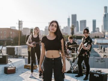 A stylish band playing music on a rooftop with city skyline in the background.
