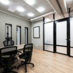 Wooden table and black office chairs placed in spacious room in new contemporary workplace