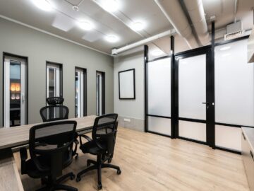 Wooden table and black office chairs placed in spacious room in new contemporary workplace