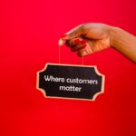 A hand holding a sign with the text 'Where customers matter' against a red background.