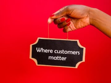 A hand holding a sign with the text 'Where customers matter' against a red background.