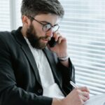 Focused businessman in office, analyzing documents while on a phone call.