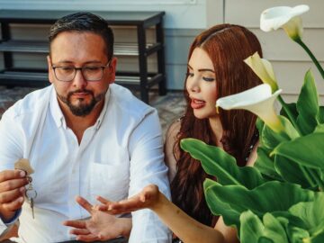 A couple sitting together outdoors, receiving keys, symbolizing a new beginning.
