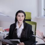 Businesswoman sitting in office reading a newspaper during a meeting.