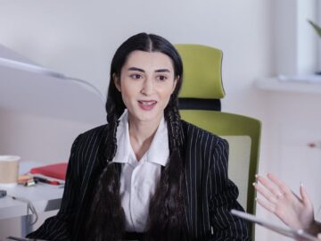 Businesswoman sitting in office reading a newspaper during a meeting.