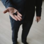 Close-up of a businessman in a suit holding car keys, inviting gesture.