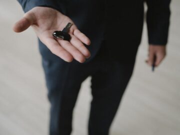 Close-up of a businessman in a suit holding car keys, inviting gesture.
