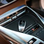 Close-up view of a luxury car's control panel featuring carbon fiber and chrome details with a key fob.