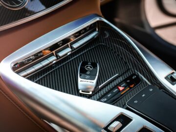 Close-up view of a luxury car's control panel featuring carbon fiber and chrome details with a key fob.