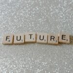 Wooden Scrabble tiles spell 'Future' against a shimmering glitter background.