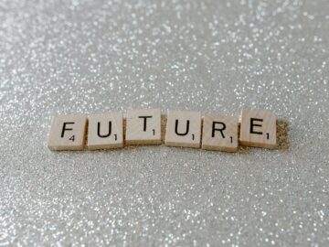 Wooden Scrabble tiles spell 'Future' against a shimmering glitter background.