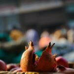 Close-up of fresh pomegranates at a bustling outdoor market, showcasing their vibrant color and organic texture.