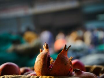 Close-up of fresh pomegranates at a bustling outdoor market, showcasing their vibrant color and organic texture.