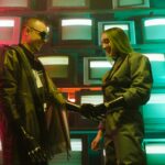 Futuristic scene of two adults shaking hands with prosthetics against a retro TV backdrop.