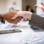 Close-up of a professional handshake over business documents, symbolizing partnership and agreement.