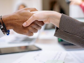 Close-up of a professional handshake over business documents, symbolizing partnership and agreement.