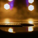 Close-up view of an acoustic guitar in warm, dramatic lighting with light reflections.