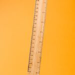 Close-up of a wooden ruler against a bright yellow surface. Ideal for school or office themes.