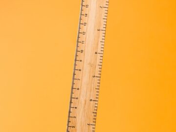 Close-up of a wooden ruler against a bright yellow surface. Ideal for school or office themes.