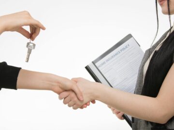A real estate transaction with a handshake and key exchange, highlighting a home insurance document.