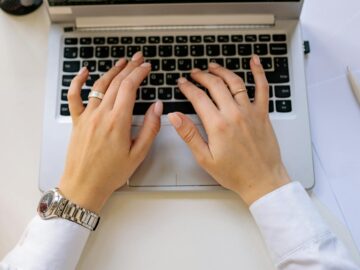 Hands typing on a sleek laptop keyboard in a bright, modern workspace. Ideal for business concepts.