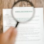 Magnifying glass focusing on 'Terms and Conditions' in a document. Ideal for business and legal themes.