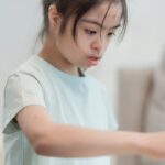 Portrait of a focused young girl with Down syndrome looking intently at a task indoors.