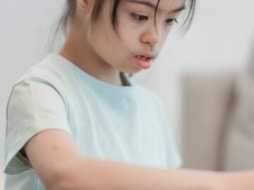 Portrait of a focused young girl with Down syndrome looking intently at a task indoors.