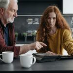 Elderly man and young woman share a poignant moment reminiscing over a photo album.