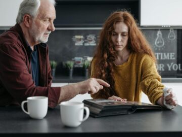 Elderly man and young woman share a poignant moment reminiscing over a photo album.