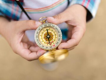 A detailed view of hands holding a vintage compass, suggesting exploration and guidance.
