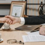 A formal handshake over a business contract in a corporate office setting.