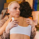 Tender embrace between two women indoors, symbolizing support and connection in a colorful setting.