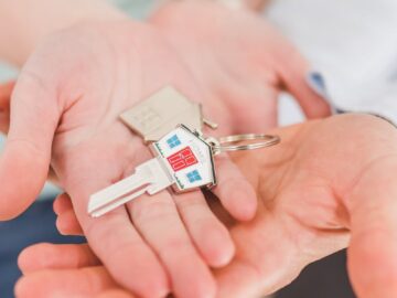 Close-up of hands holding a key with a house-shaped keychain, symbolizing new beginnings.