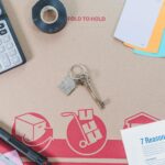 Flat lay of home buying essentials with calculator, keys, tape, and color swatches.