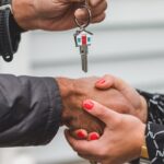 Close-up of a handshake with a house key, symbolizing real estate transactions.