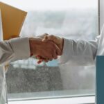 Two business professionals shaking hands indoors, symbolizing agreement.