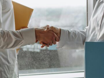 Two business professionals shaking hands indoors, symbolizing agreement.