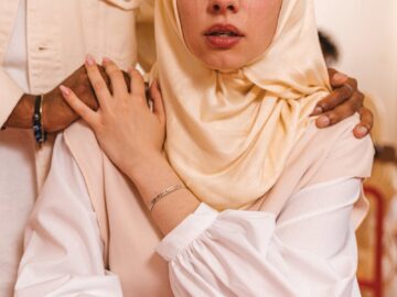 A woman in a hijab receives comfort from a supportive companion in an emotional moment.